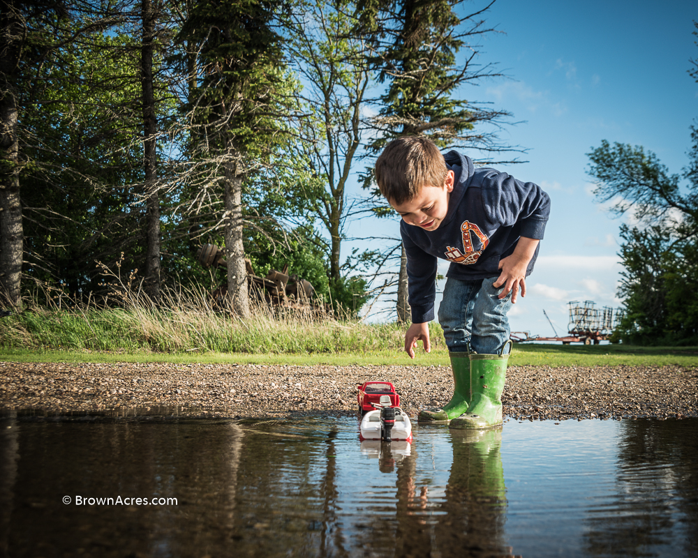 Boy with boat in a puddle